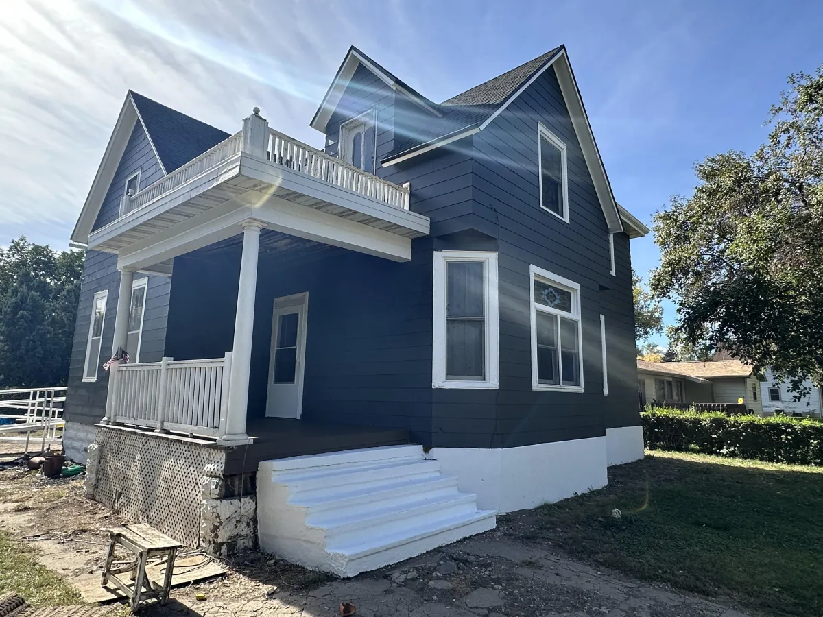 After exterior paint: fresh white trim and smooth dark blue siding on updated home