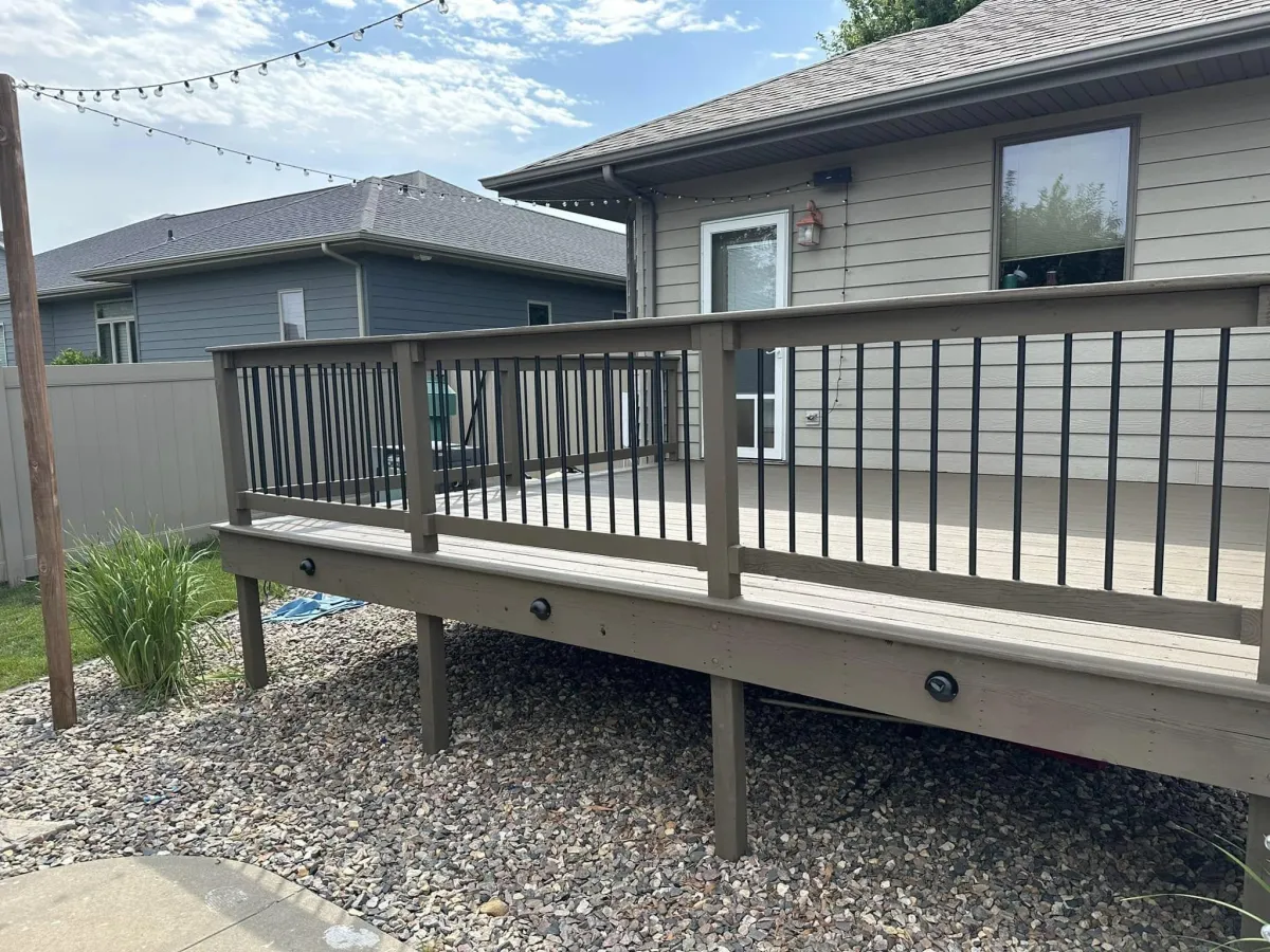 Refinished outdoor deck with clean railings, neutral paint, and pebble landscaping