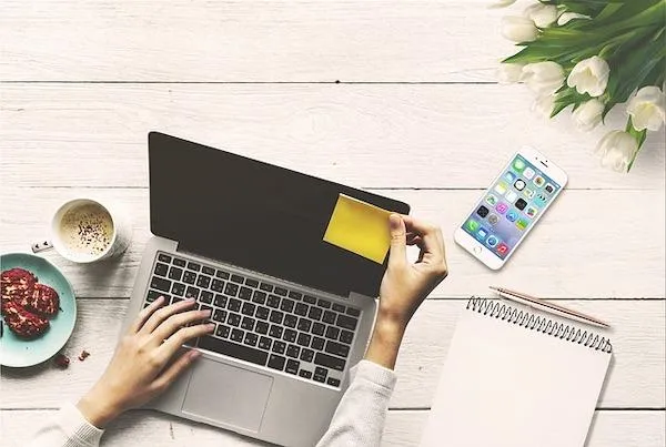 Laptop with woman typing and post it note