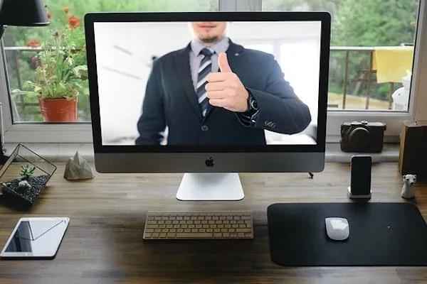 Man in suit with thumbs up displayed on laptop computer screen 