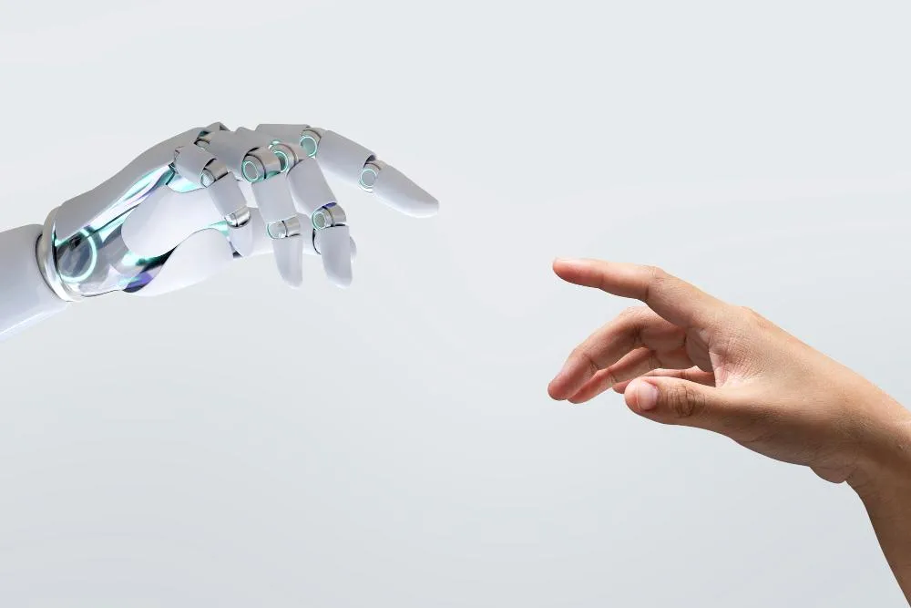 Close‑up of a human index finger and a robotic finger reaching toward each other, highlighting the connection between people and technology.