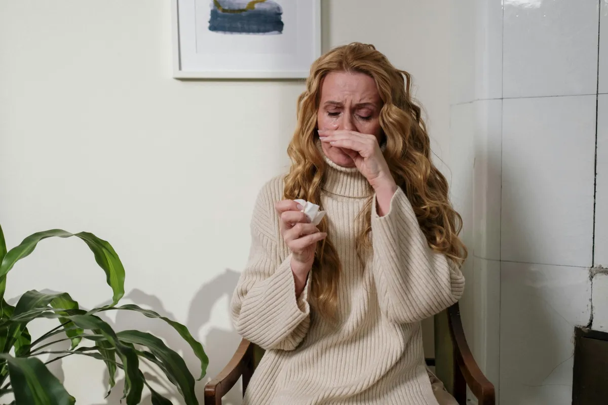 woman holding tissue with red nose