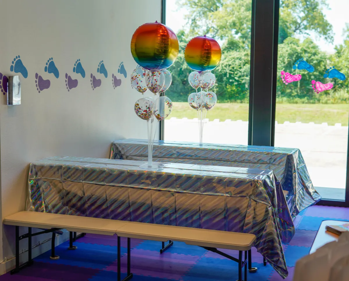 Rainbow balloon birthday party table setup with colorful decorations at Wild Child indoor playground in Bastrop, TX