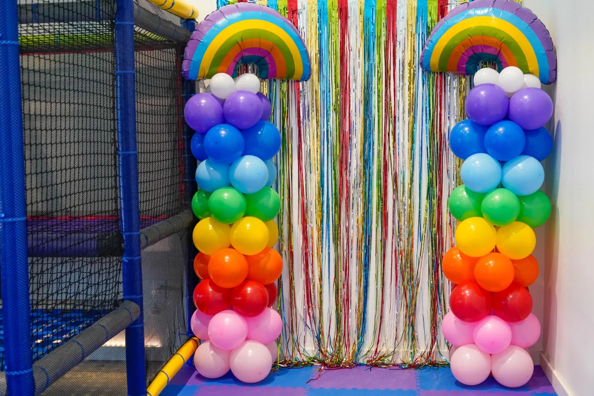 Rainbow balloon photo backdrop at Wild Child indoor playground in Bastrop, TX, set up for a kids birthday party