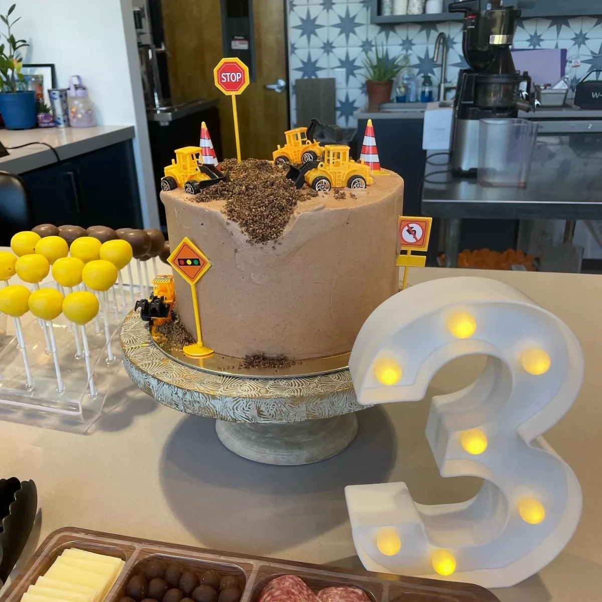 Construction site themed birthday cake with toy trucks and chocolate dirt for a 3-year-old party at Wild Child in Bastrop, TX