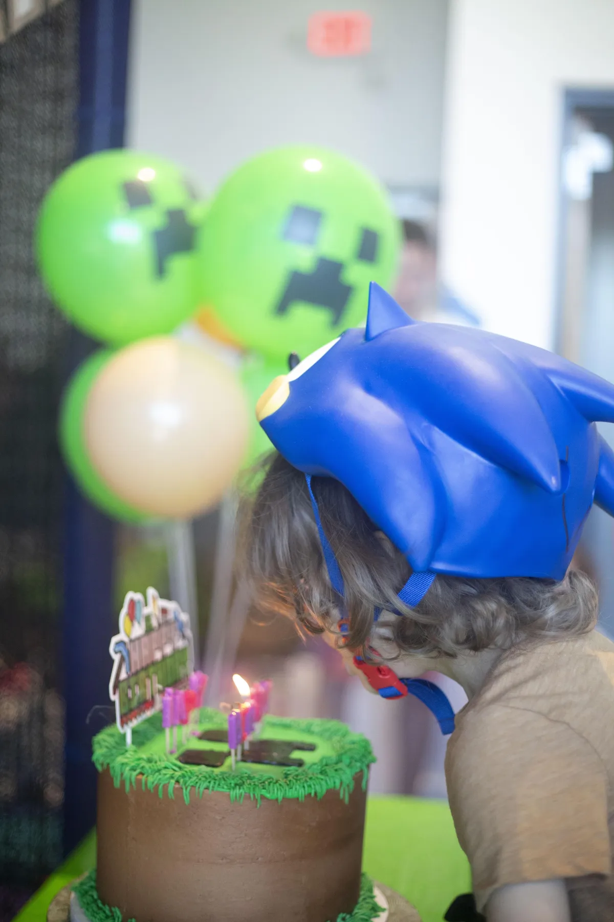 Boy blowing out birthday candles on a Minecraft cake during a party at Wild Child indoor playground in Bastrop, TX