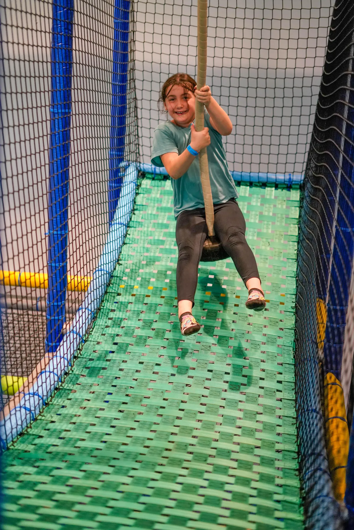 Girl swinging inside Wild Child indoor playground in Bastrop, TX during open play