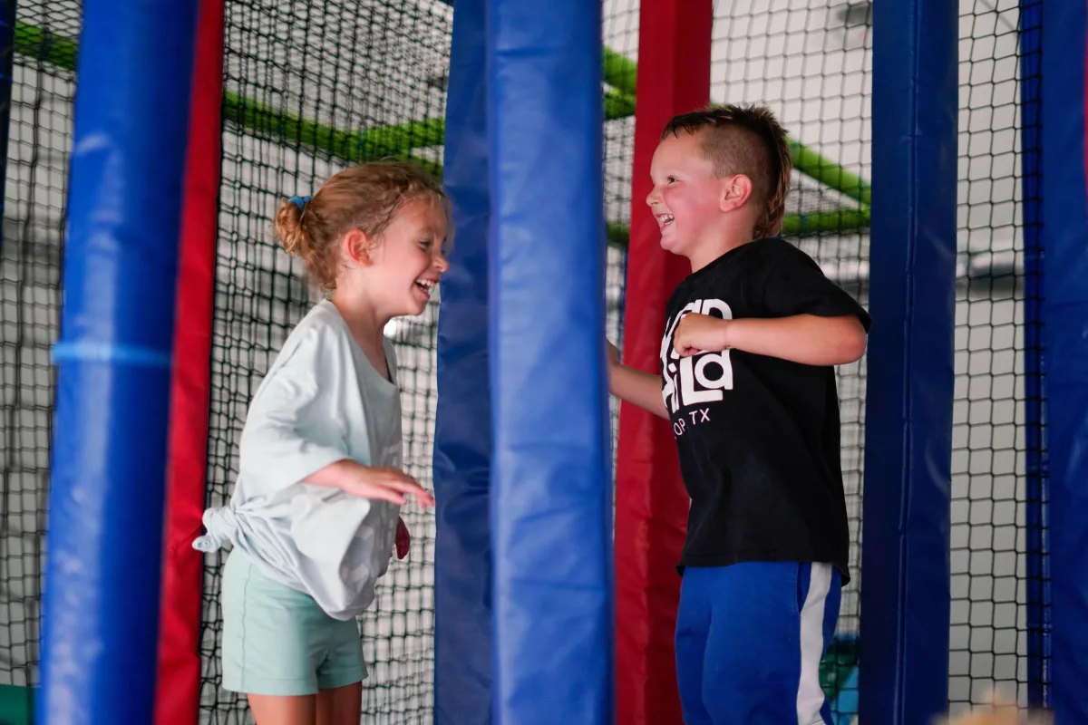 Girl and boy bouncing together inside Wild Child indoor playground in Bastrop, TX