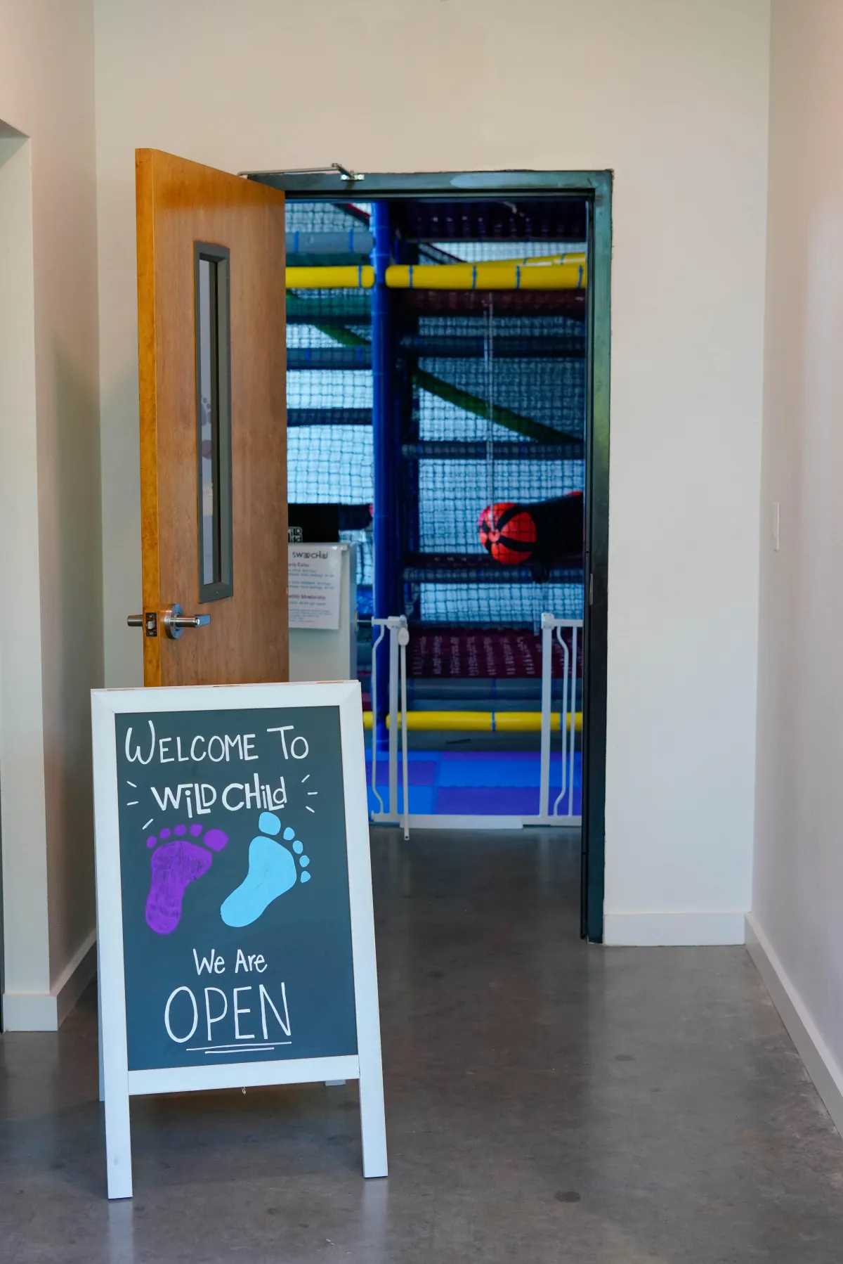 Open front door with a welcome sign at Wild Child indoor playground in Bastrop, TX
