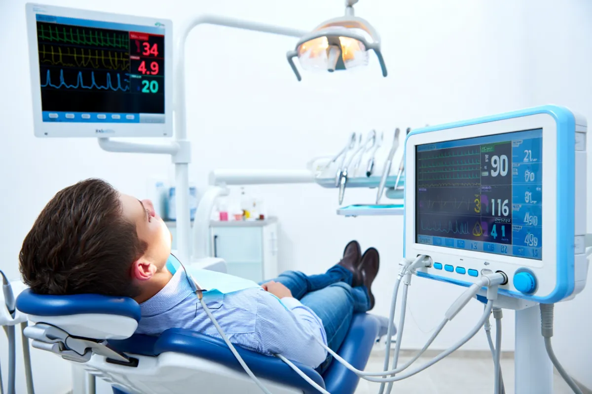 Young man sedated laying back in dentist chair eyes closed
