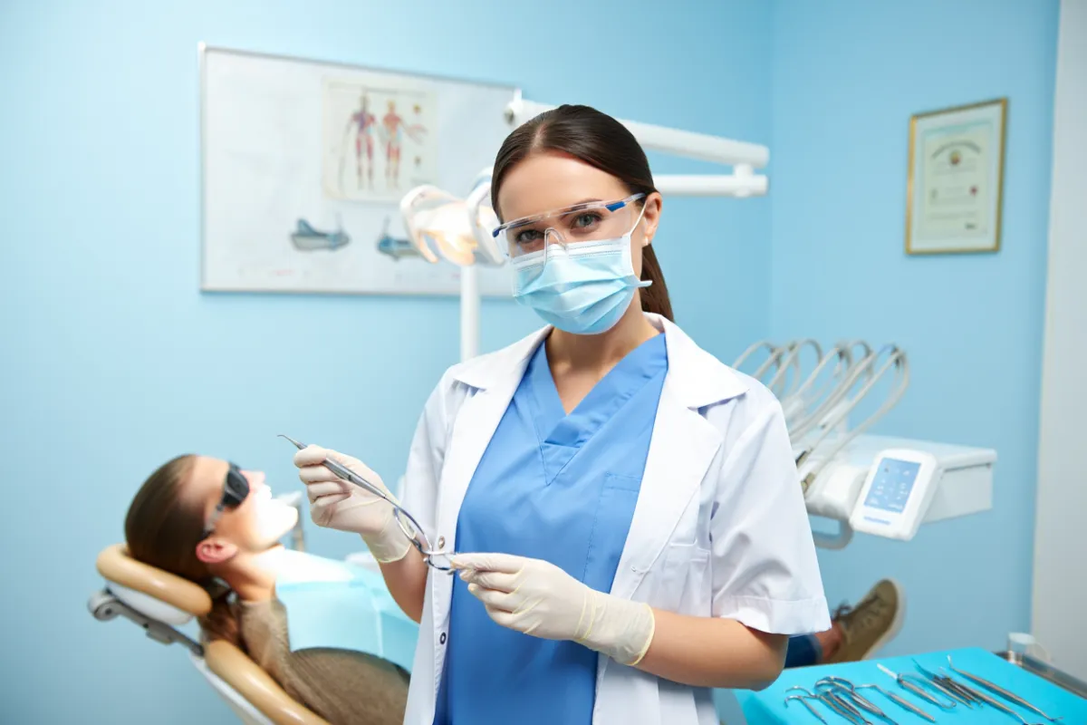 female dentist working on a patent wearing mask scrubs