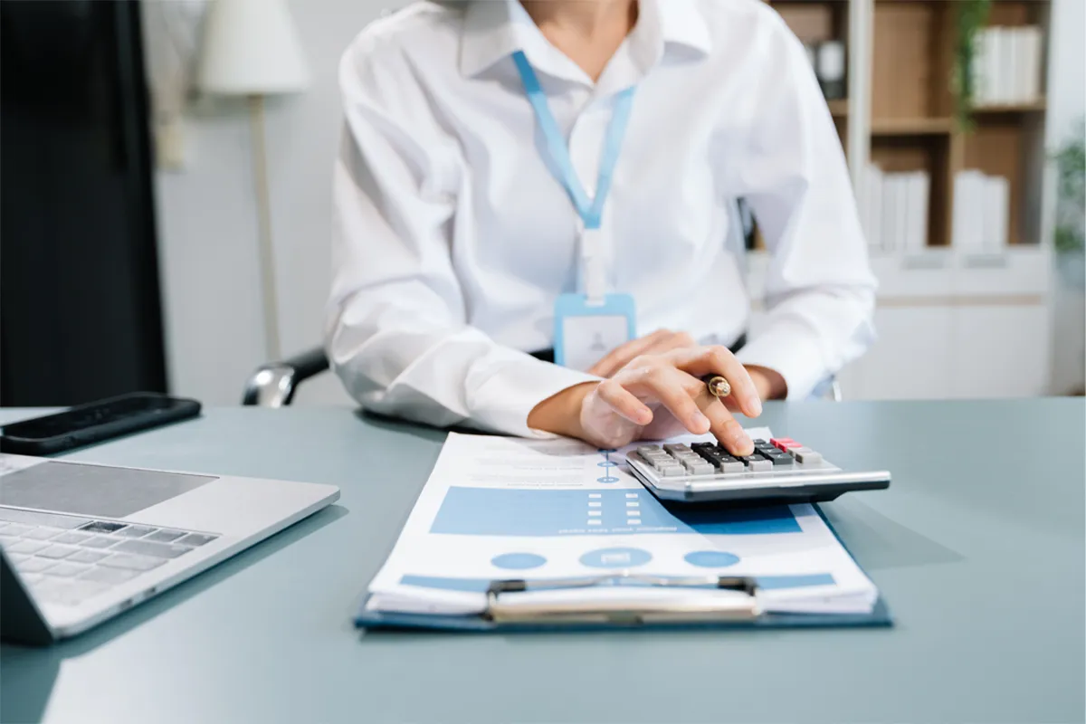 Dentist calculating her break even analysis poitn for her new dental practice using a calculator