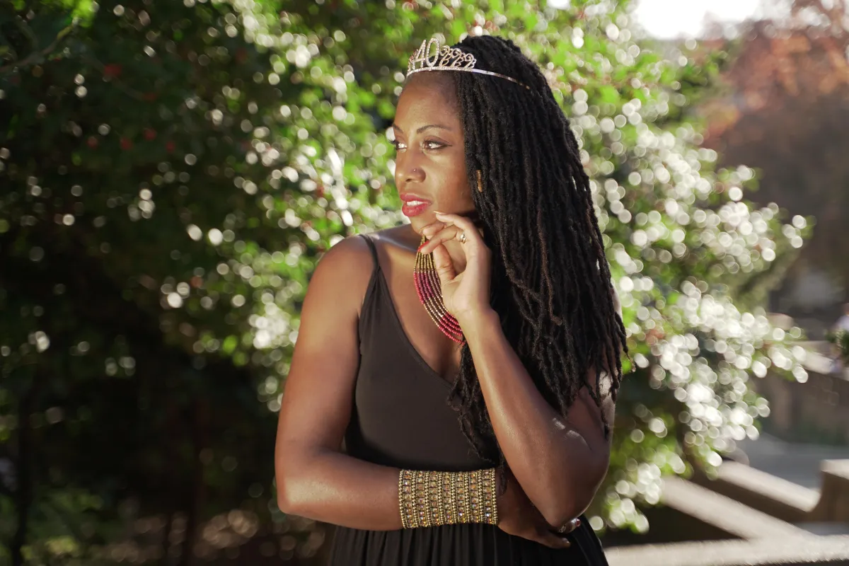 Elegant African American woman with a mini crown and green leaves, showcasing natural beauty.