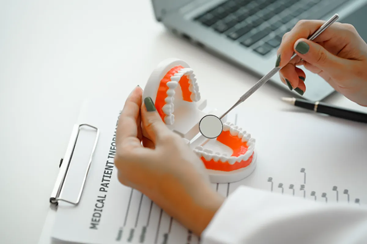 Dentist at her desk looking at a pair of fake teeth