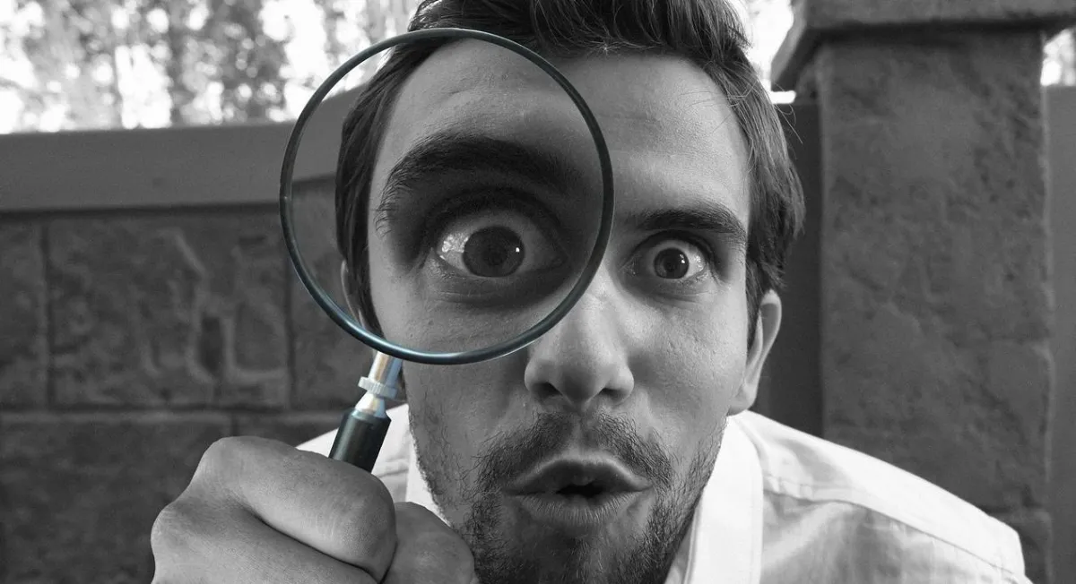 A real estate agent looking into a magnifying glass trying to find real estate leads