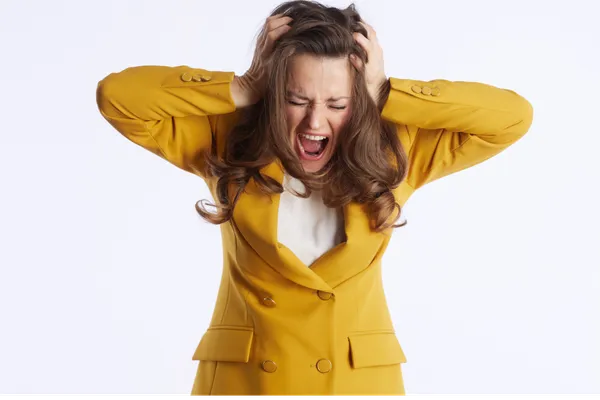 femme d'une trentaine d'année debout en panique qui se tient la tête avec ses mains faisant une crise de guérison