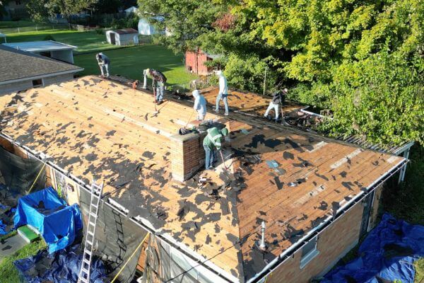 Home roof replacement in progress with exposed decking and new shingles being installed, suburban neighborhood, realistic, professional