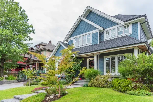 Clean suburban home with blue siding, well-maintained yard, and manicured landscape