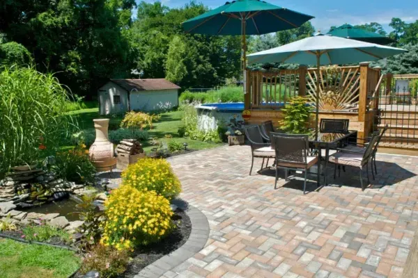 Beautiful backyard patio with paver stones, outdoor dining area, garden, and swimming pool