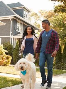 couple walking fluffy dog