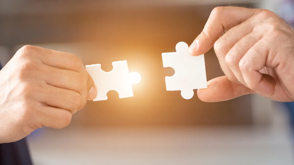 two hands putting puzzle pieces together to represent human connection