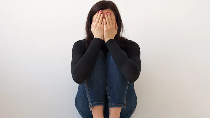 A woman covering her face out of shame in need of shame therapy