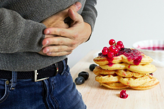 man in pain next to a cake