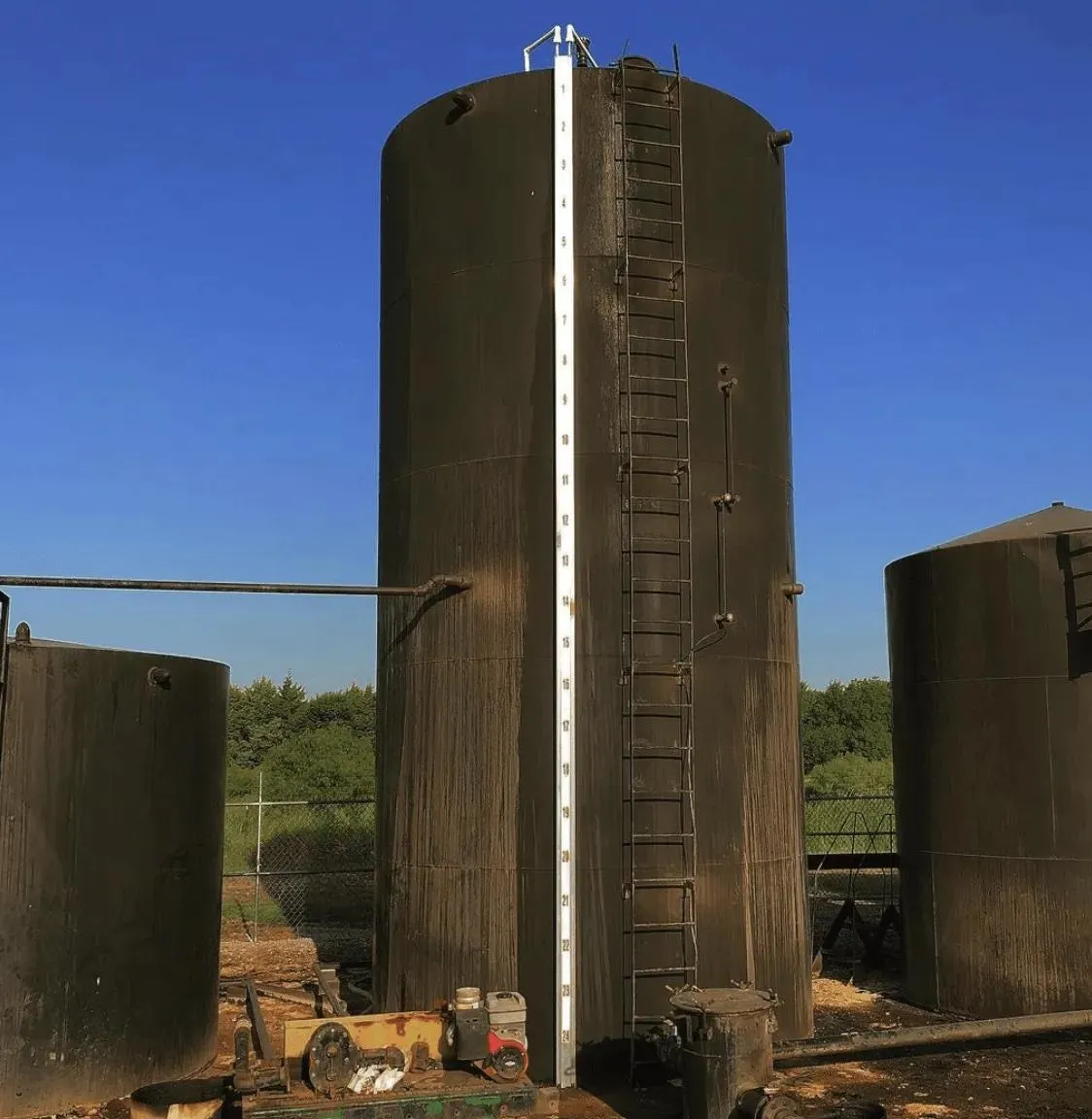 Black storage tank with an attached tank float gauge and a steel ladder, highlighting the adaptability for installation on both old and new tanks. Commonly used for fuel or water level monitoring in transportation or energy industries.