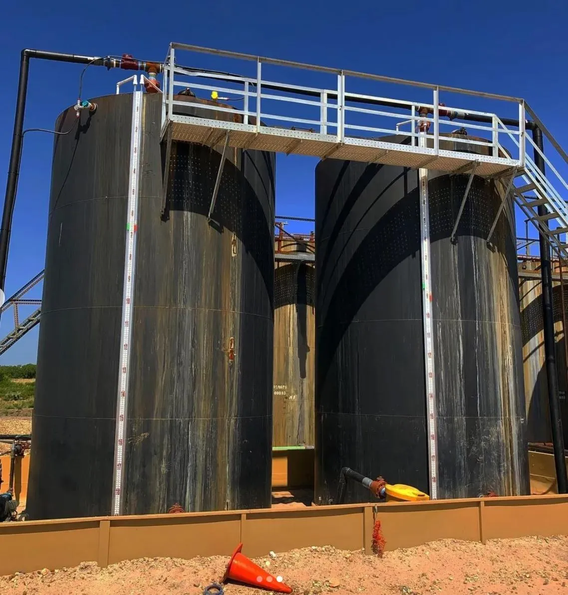 Black industrial tanks with external liquid level gauges for tanks, showcasing versatility for installation on both old and new tanks. Ideal for industries like oil refining or large-scale fuel storage.