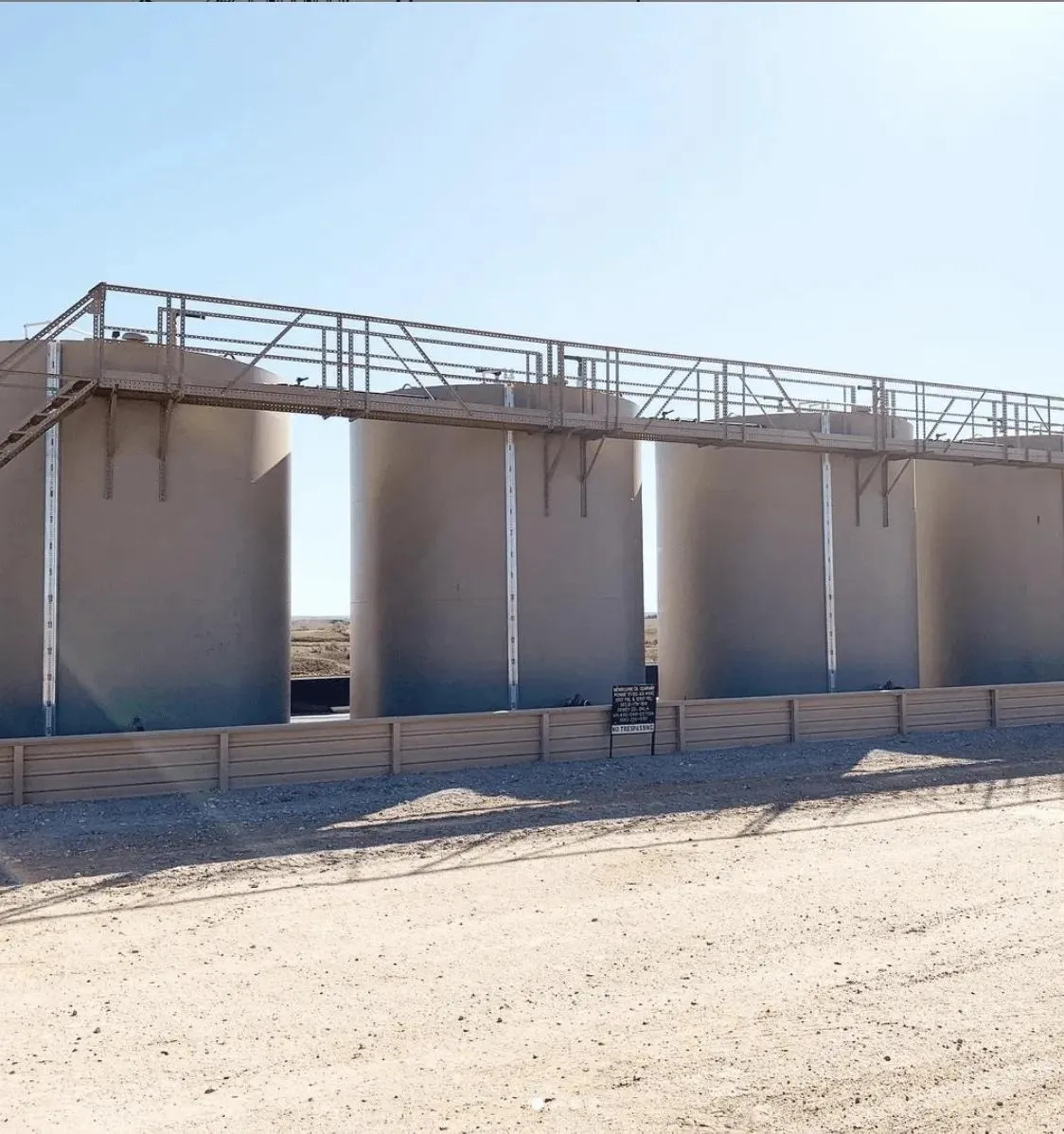 Beige industrial tanks with integrated metal walkways and external fluid level indicators, suitable for monitoring liquid levels in water treatment plants or bulk chemical storage facilities. The tanks demonstrate high operational capacity and accuracy.