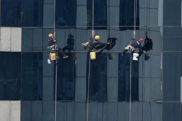 3 people cleaning windows on a large building