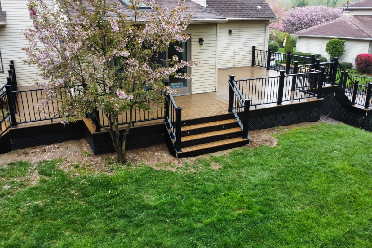 Composite deck with black railings beside a flowering cherry tree - pergola installation by Prime Decks in Wilmington, DE