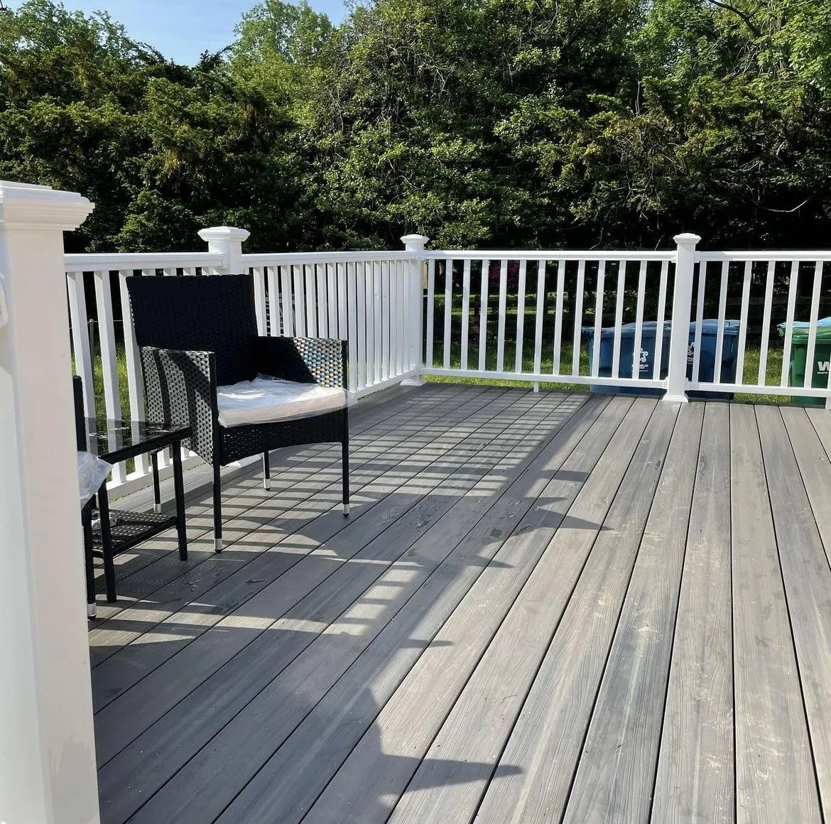 Grey composite deck boards with white railing and wicker patio chairs - deck design by Prime Decks in Wilmington, DE