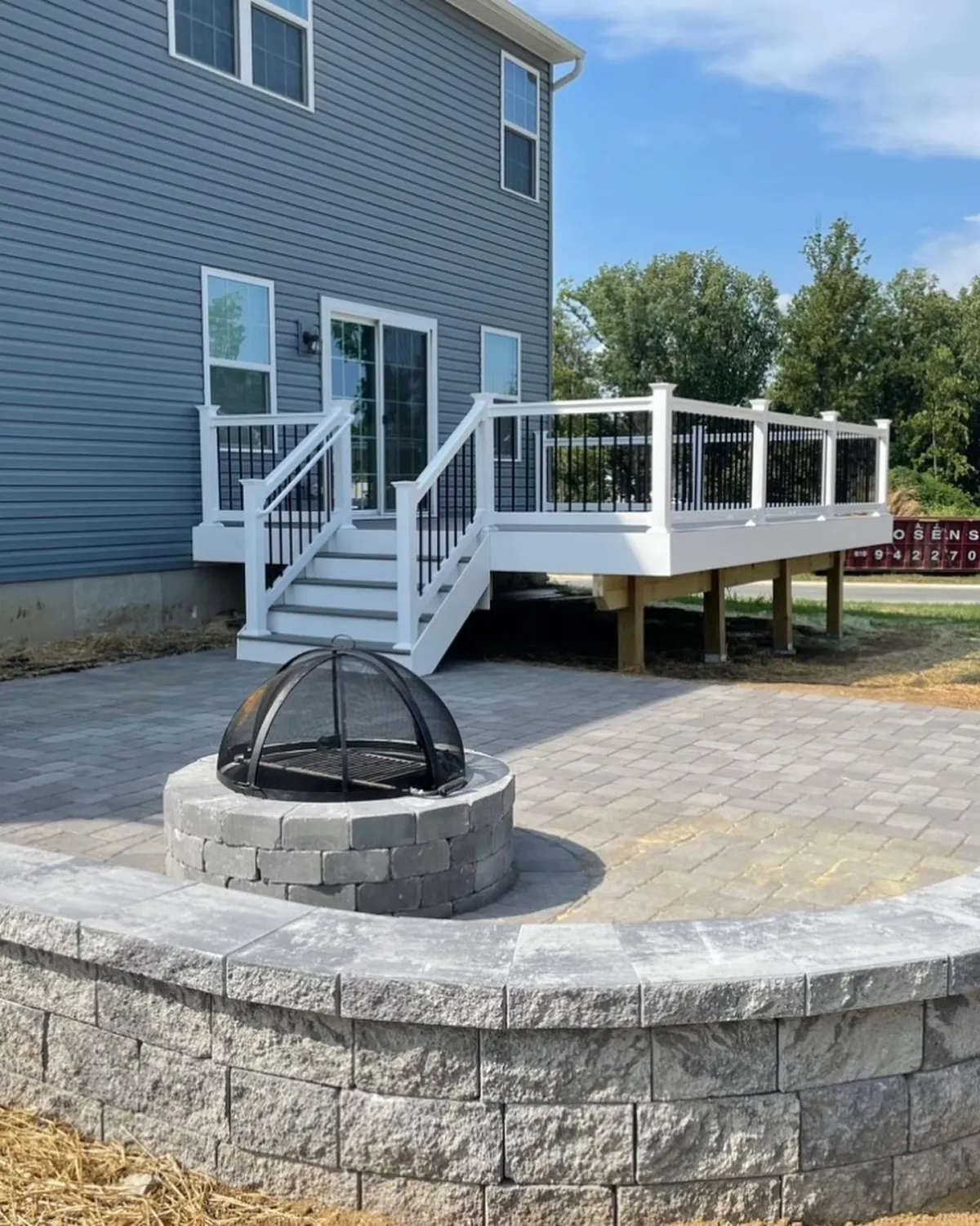 Composite deck with white railings, paver patio and stone fire pit - deck design by Prime Decks in Wilmington, DE