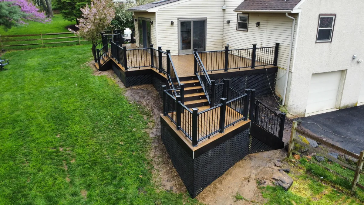 Tan composite deck with black aluminum railings, stairs and lattice skirting - deck building by Prime Decks in Pike Creek, DE