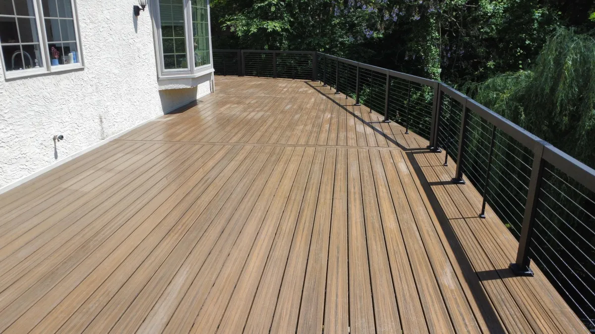 Brown composite deck with black cable railings along a white stucco home in Wilmington, DE