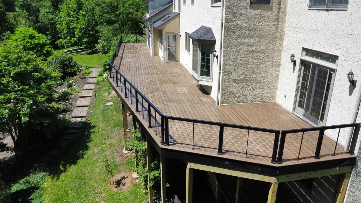 Long elevated composite deck with black cable railing along a stucco home - deck building by Prime Decks in Bear, DE