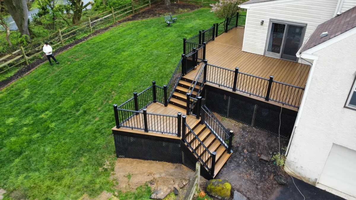 Composite deck with black railings, dual staircases and lattice skirting - deck building by Prime Decks in Bear, DE