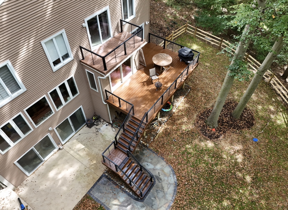 Two-story composite deck with black railings and staircase on a tan home - deck building by Prime Decks in Wilmington, DE