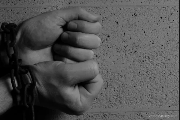 Hands bound in chains against a concrete wall, symbolizing the struggle to break free from limitations and achieve personal sovereignty.