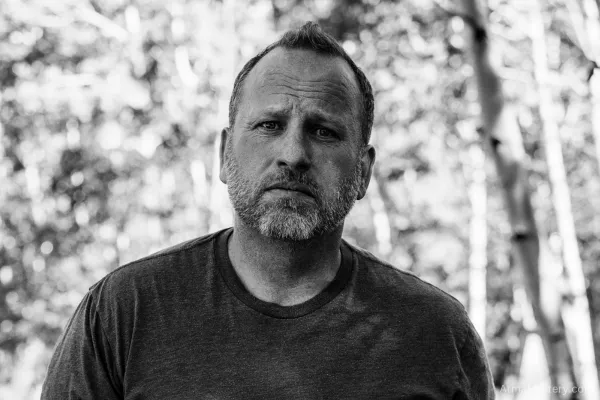 Black and white portrait of a contemplative man in nature, symbolizing introspection, transformation, and breaking free from limiting thought patterns.