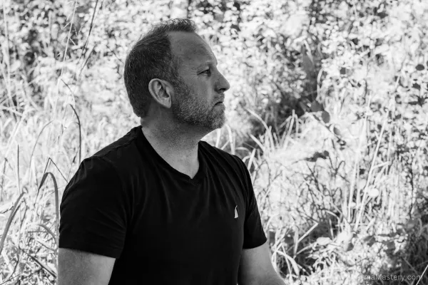 Man sitting outdoors in a peaceful, meditative state, surrounded by natural greenery, symbolizing reflection and personal growth.