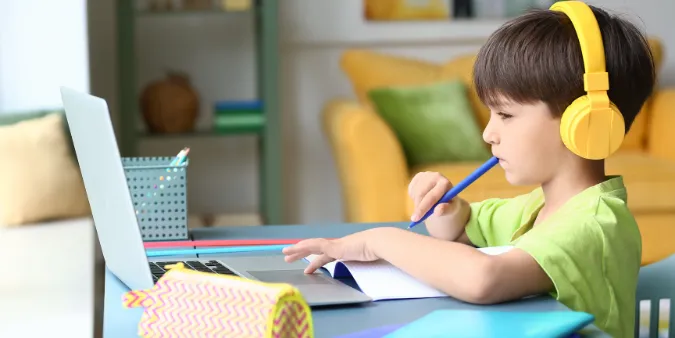 young boy with headphones studying at his desk