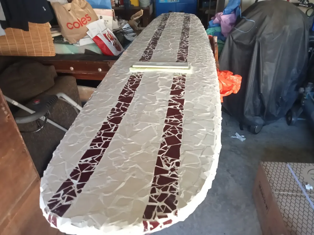 Cream longboard letterbox with twin maroon mosaic racing stripes on the workbench