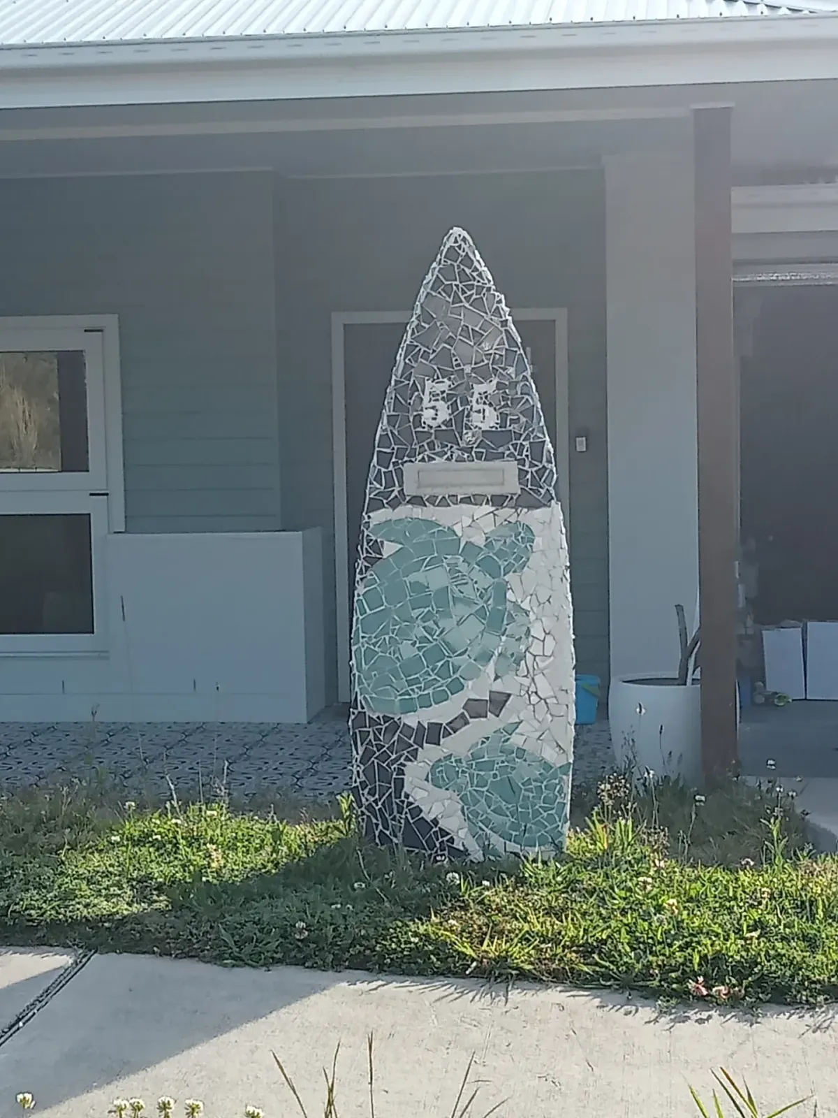 Grey and teal patterned mosaic surfboard letterbox installed at a new build