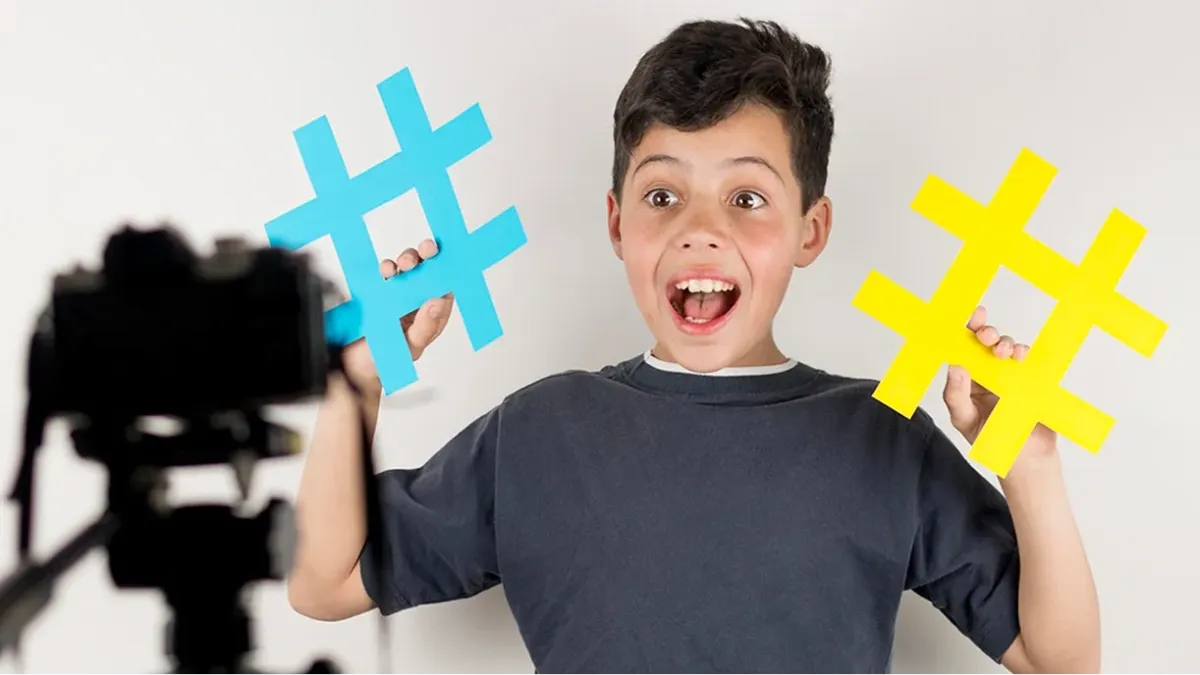 Boy smiling at a camera, holding colorful # signs