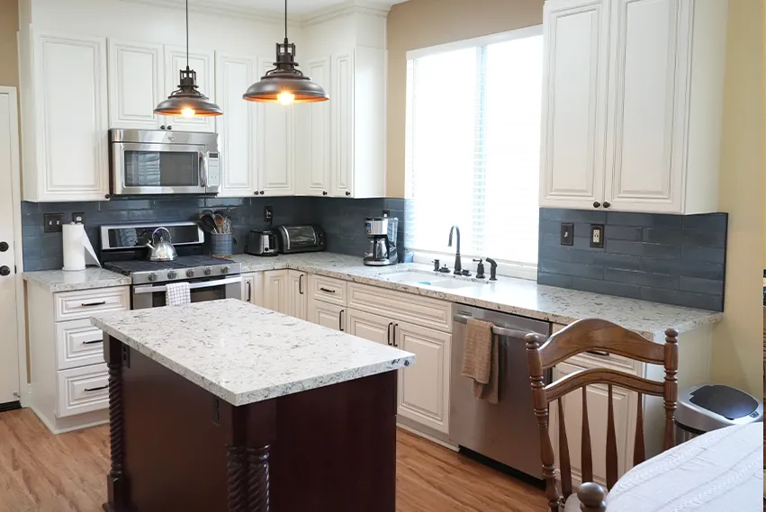 Modern kitchen with white cabinetry, stainless steel refrigerator, granite countertops, pendant lights, and a dark subway tile backsplash.