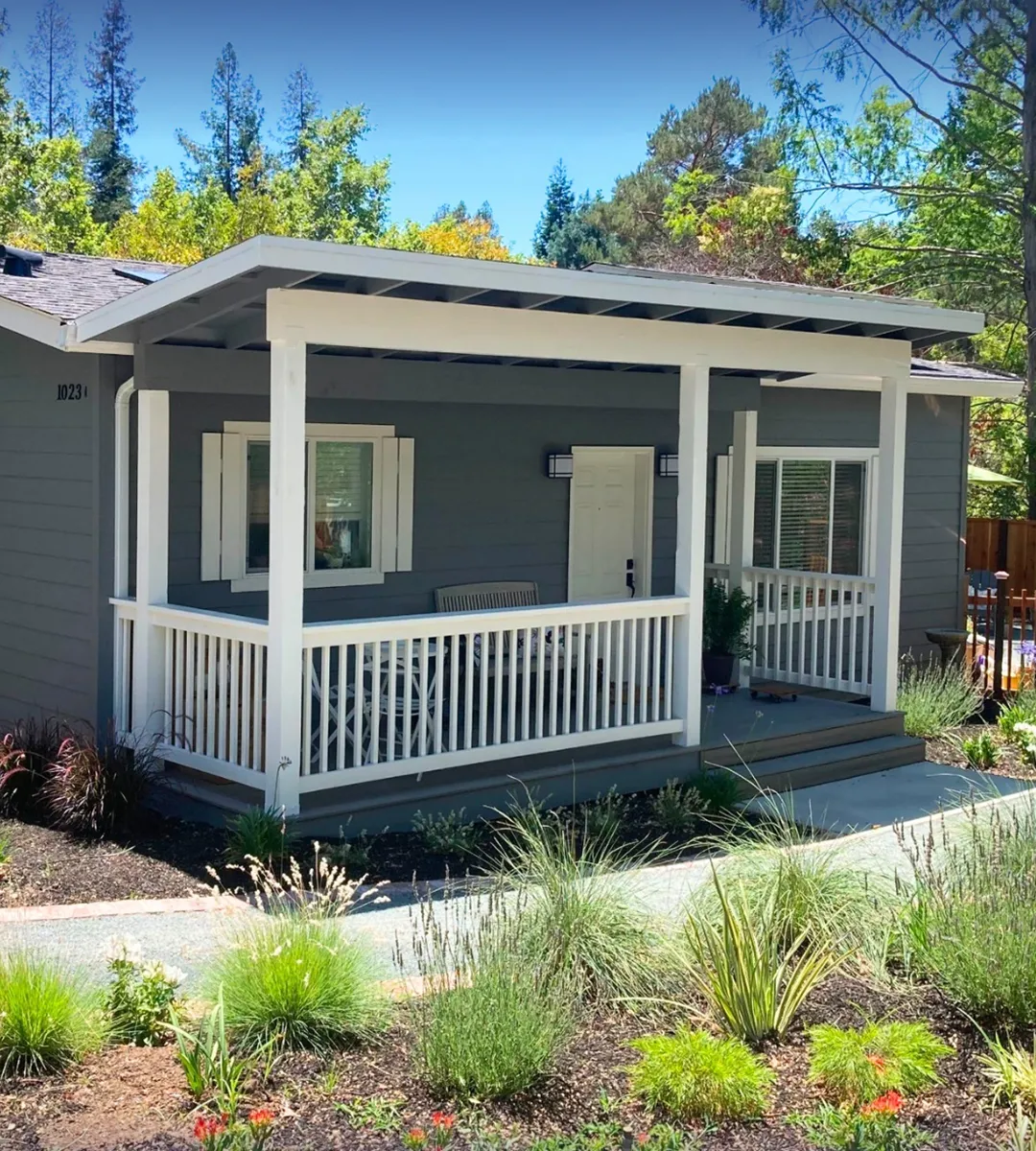 Cozy ADU with dark gray siding, white accents, a covered front porch, and landscaped surroundings.