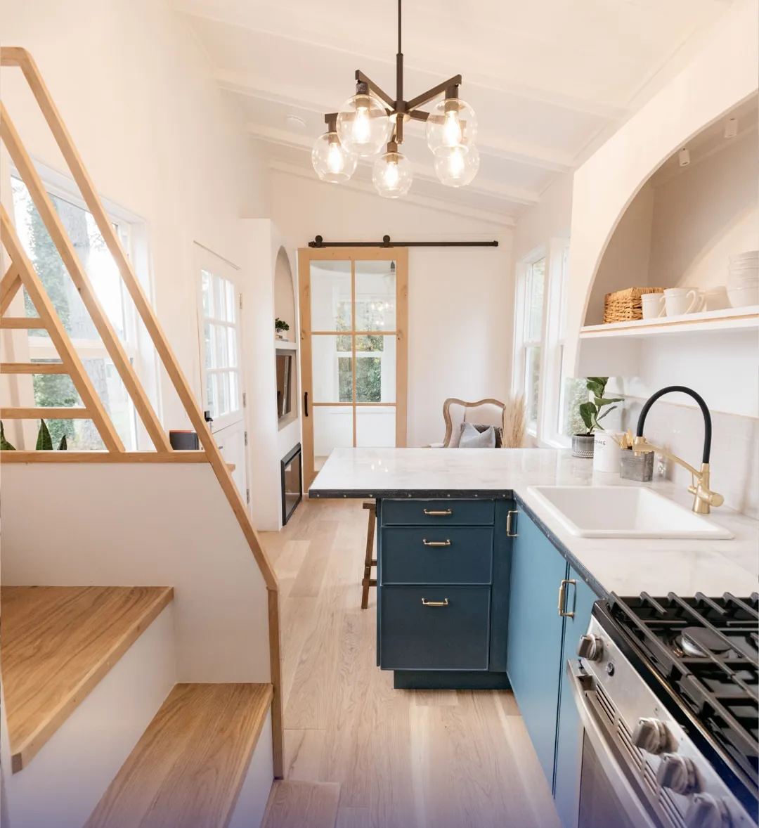 Stylish ADU interior with a loft, blue kitchen cabinets, marble countertops, sliding barn door, and warm wood accents.