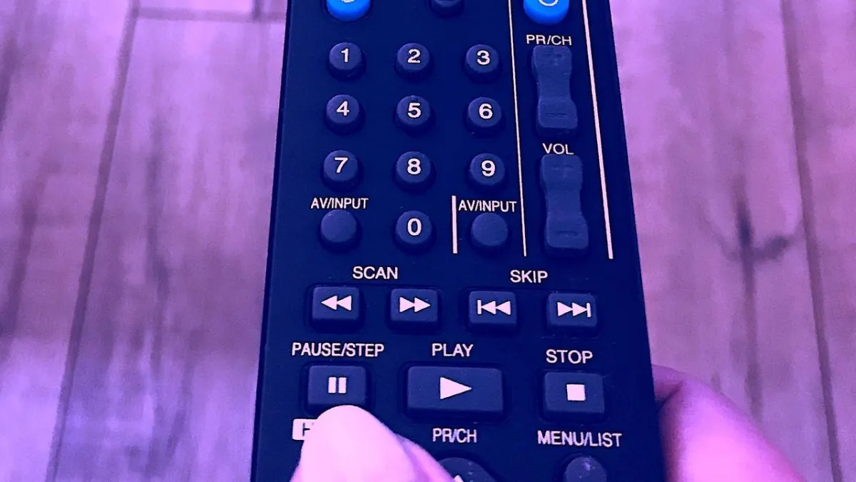 picture of a TV remote with finger on the pause button